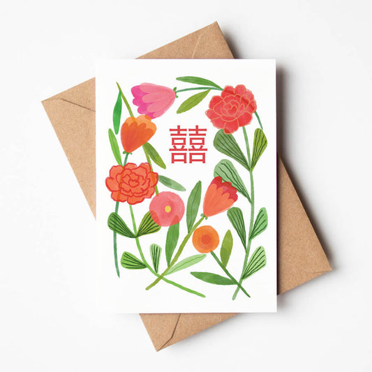 A greeting card featuring red and pink stylised flowers with a Chinese Double Happiness charactre