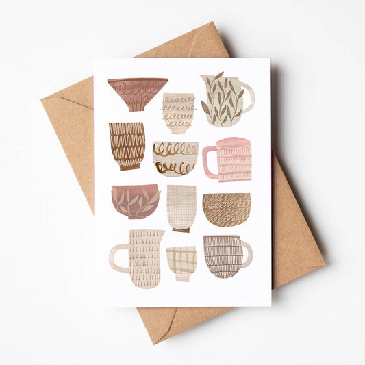 A greeting card featuring a digital reproduction of collage cups, bowls and jugs. Card is resting on a brown envelope