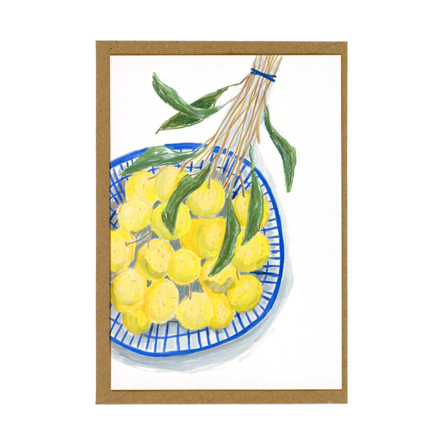 A illustrated greeting card of longan fruit in a blue basket. The card sits on top of a brown envelope.
