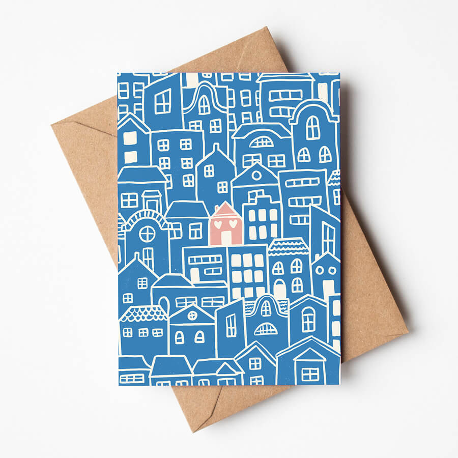 An eco friendly illustrated card showing a single pink house with hearts for windows surrounded by blue coloured houses