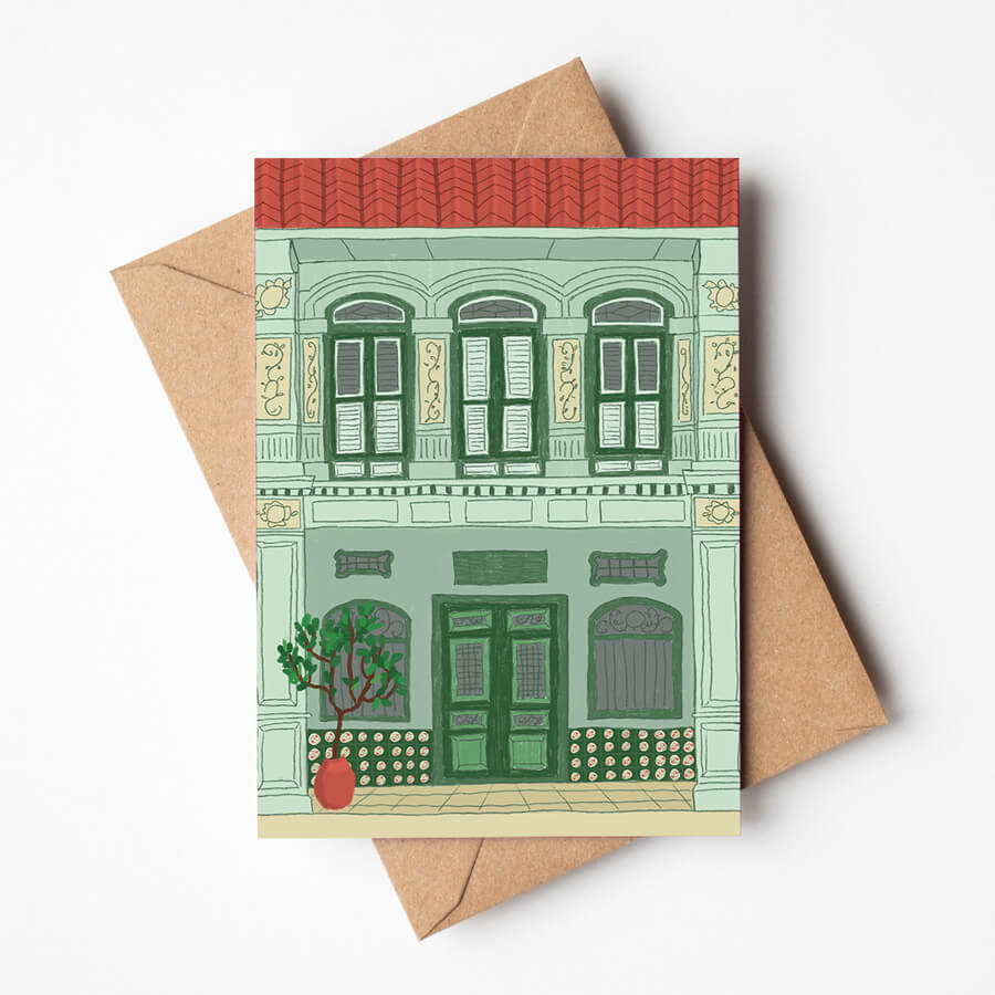 A greeting card featuring a heritage shophouse typically found in Malaysia and Singapore. The card is on top of a brown paper recycled envelope