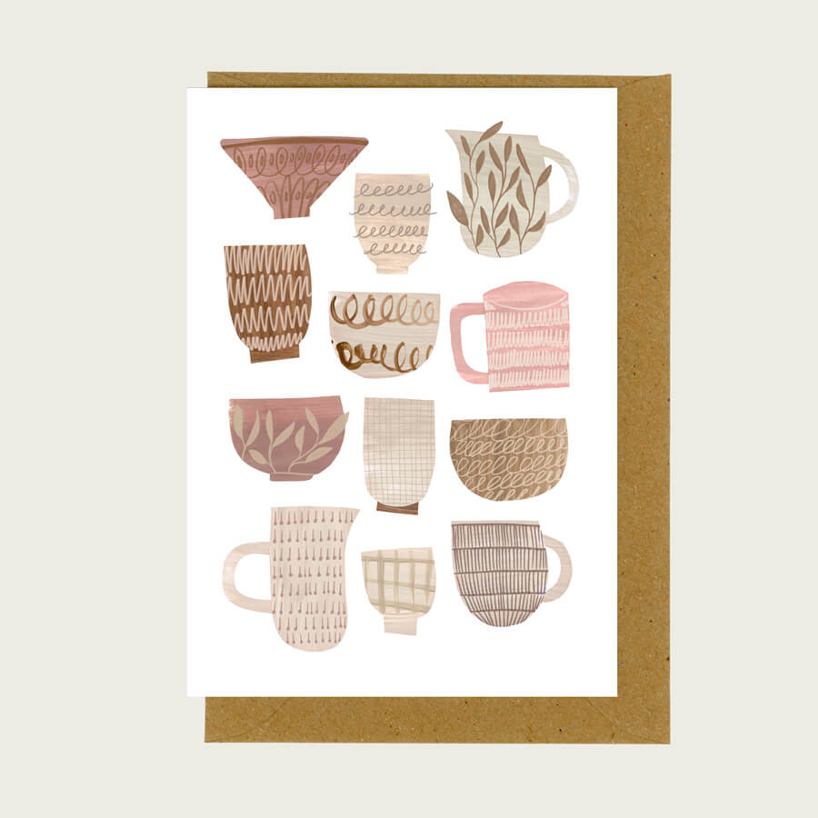 A greeting card of pink and brown ceramics with a brown paper envelope