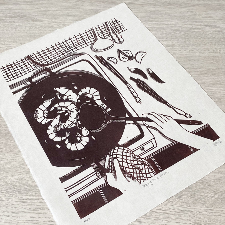 An original block print by Bert and Roxy depicting cooking of King prawns with garlic, chilli and spring onion in a large wok over a gas stove. Handcarved and handprinted in brown ink on Japanese washi paper