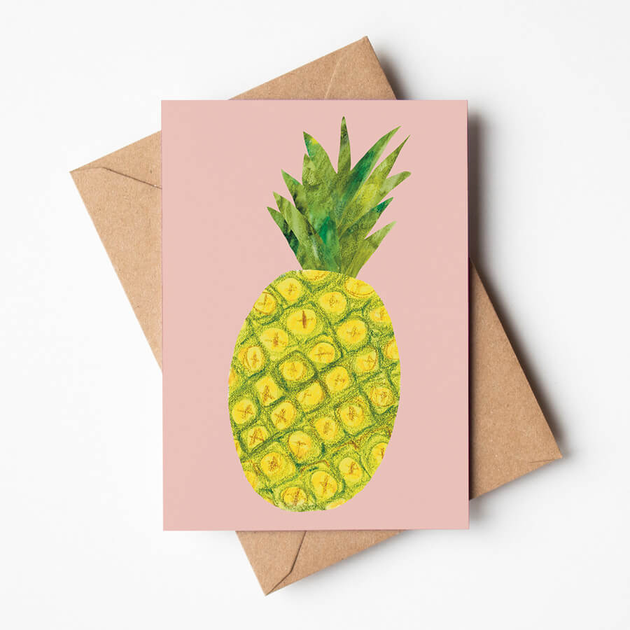 A eco friendly greeting card featuring a collaged mixed media pineapple on a light pink background. Displayed with a brown paper envelope. 